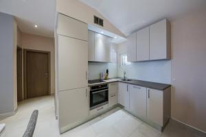 a large white kitchen with white cabinets and appliances at Apartmani Savin in Brodarica