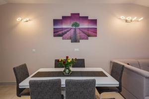 a dining room with a table and a painting on the wall at Apartmani Savin in Brodarica