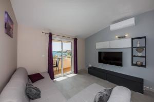 a living room with a couch and a tv at Apartmani Savin in Brodarica