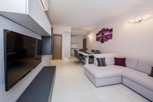 a living room with a white couch and a desk at Apartmani Savin in Brodarica