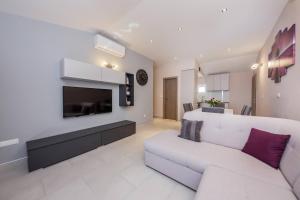 a living room with a white couch and a tv at Apartmani Savin in Brodarica