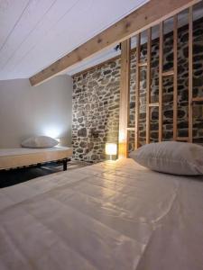 a bedroom with a bed and a stone wall at La Maison Du 146 in Flavin