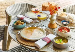 a wooden table topped with plates and bowls of food at Hôtel Barrière Le Gray d'Albion in Cannes