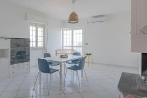 a white kitchen with a white table and blue chairs at Ferrante - YourPlace Abruzzo in Fossacesia