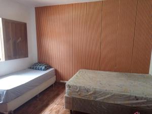a bedroom with two beds and a large wooden wall at Casa térreo na ilha in Itaparica Town