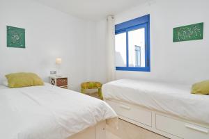 two beds in a white room with a window at Penthouse by the beach in Torrox Costa