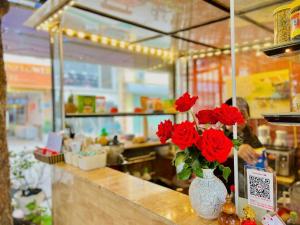 a vase filled with red flowers on top of a counter at Noi Bai Sunflower Hotel in Noi Bai