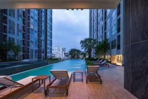 a swimming pool in a building with chairs and tables at The Base海景网红顶层无边泳池 双卧室套房 in Pattaya Central +37 photos