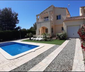 a villa with a swimming pool in front of a house at Villa Naomi in Les tres Cales