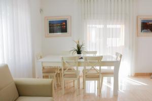 a white dining room with a white table and chairs at Cozy Apartment Rocamar in Sant Pere de Ribes