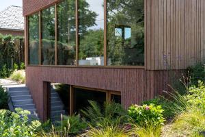a house with glass windows and stairs in a garden at Sweet Valley Cozy in Zutendaal