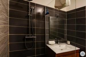 a black tiled bathroom with a shower and a sink at Jardin Tropical 3 - 45 m2 - La Saline Les Bains in Saint-Paul +13 photos