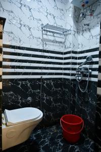 a bathroom with a toilet and a red bucket at Hotel Hari Gopal in Varanasi +79 photos