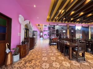 ein Restaurant mit lila Wänden, Holztischen und Stühlen in der Unterkunft Changpuak Boutique House in Chiang Mai