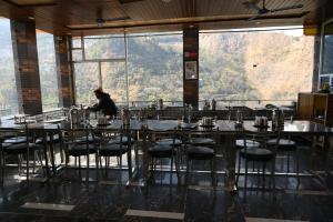 a person sitting at a table in a restaurant with a view at RK Residency Ukhimath in Ukhimath