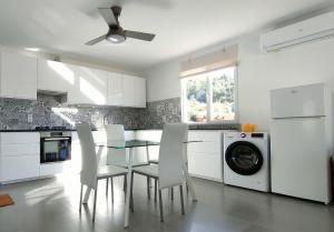 a kitchen with a dining room table and white cabinets at Casa-Diospiro-villa-for-4P-baby-with-private-pool in São Bartolomeu de Messines