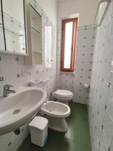 a white bathroom with a sink and a toilet at Casa Naldina in Marciana Marina