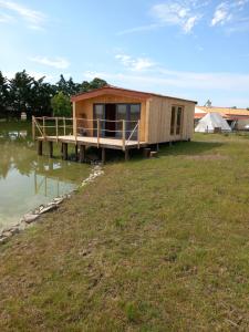 a house on a dock on a body of water at Chalet chez le breton des marais in Bouin