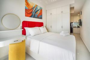 a white bedroom with a large bed and a mirror at Otis Soho Saigon Balcony Apartment in Ho Chi Minh City