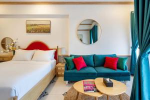 a hotel room with a bed and a blue couch at Otis Soho Saigon Balcony Apartment in Ho Chi Minh City