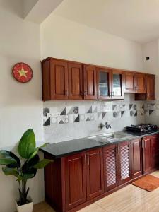 a kitchen with wooden cabinets and a clock on the wall at An Yên Homestayy huế in Thôn Lại Thê