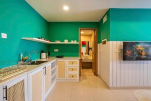 a green kitchen with white cabinets and a green wall at Otis Soho Saigon Balcony Apartment in Ho Chi Minh City