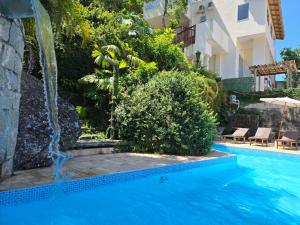 a swimming pool with a waterfall next to a building at Apartamentos Casa da Pedra in Ubatuba