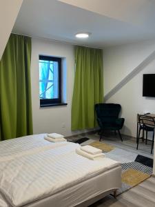 a bedroom with a bed with green curtains and a chair at Nostalgia restaurant & pension in Rimavská Sobota +66 photos