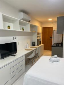a kitchen with white cabinets and a large television at Flat em Boa Viagem Recife PE in Recife