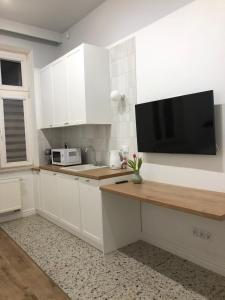 Una cocina con gabinetes blancos y un televisor de pantalla plana. en Sands Sopot Apartments 1, en Sopot 2 fotos más
