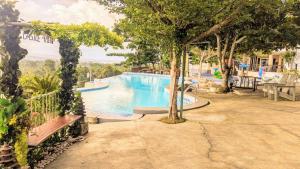 a swimming pool in a resort with a bench and trees at Castle View Hotel Samal in Magamomo