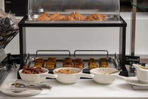 a counter with bowls of food and pastries on a shelf at Oniro Boutique Hotel in Toroni