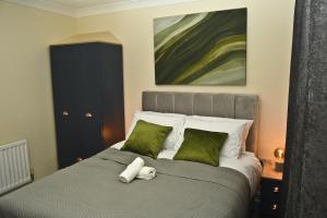 a bedroom with a bed with green pillows and a painting at Warrington Suites by Relax Stays in Warrington