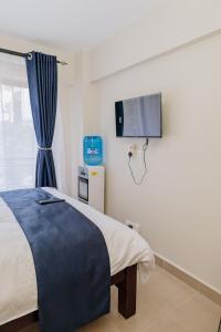a bedroom with a bed and a tv on the wall at Miiza Realtors in Nairobi