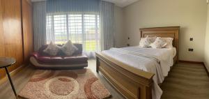 a bedroom with a bed and a chair and a window at charming retreat in Gaborone