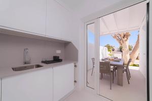 a kitchen with white cabinets and a table with chairs at Villa Nina Lanzarote in Puerto del Carmen