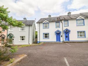 una grande casa bianca con porte blu in un parcheggio di 18 Dalewood a Glengarriff