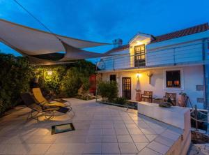 a patio with chairs and an umbrella in front of a house at Rustic Villa Rudine in Dobrinj