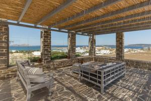 a patio with two chairs and a table and some water at Villa Vireya in Naousa