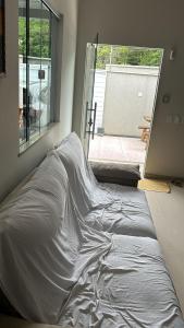 a bed sitting in a room next to a window at Casa aconchegante in Rio das Ostras +2 photos