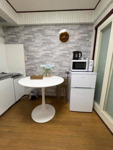 a small kitchen with a white table and a microwave at 日韓マンション305 in Tokyo