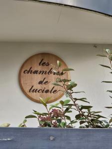 a wooden sign on a wall with a plant at Les chambres de Luciole in Asnières-lès-Dijon