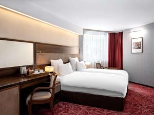 una camera d'albergo con un letto grande e una scrivania di Movenpick hotel Sarajevo a Sarajevo