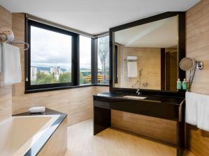 un bagno con vasca, lavandino e specchio di Movenpick hotel Sarajevo a Sarajevo