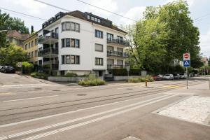 an empty street in front of a white building at BASELiving Studio - Near ESC - Bahnhof SBB - St Jakob in Basel