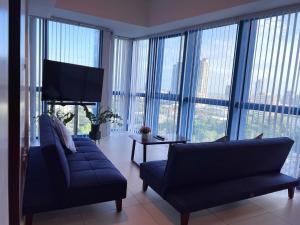 a living room with a blue couch and large windows at The City Escape in Cebu City