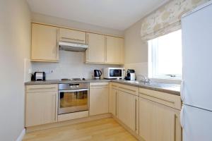 cocina con armarios de madera y nevera blanca en Fonthill Apartment - central, free parking off street en Aberdeen