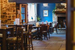 a dining room with tables and chairs and a fireplace at Black Horse Hotel in Grassington