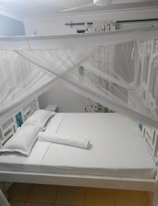 a white bed in a room with white shelves at Haven Apartments in Malindi +19 photos