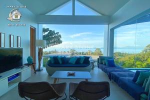 a living room with blue furniture and a large window at Villa Azula - Stunning Seaview in Ban Bang Po